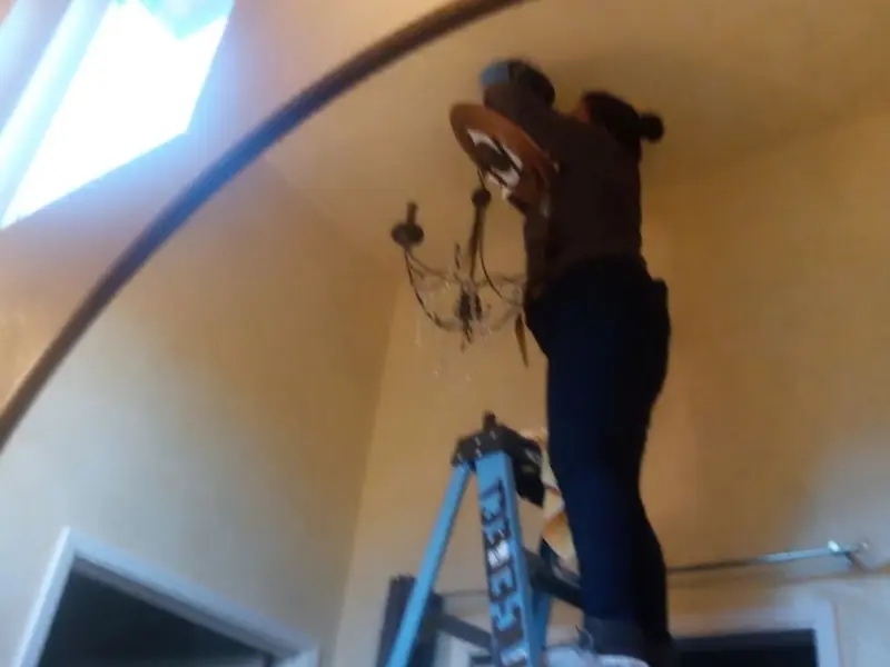 Electrician installing a chandelier in a Prospect residence